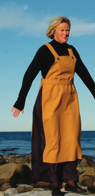 Kvinne i okergult Leikaren-kostyme ved havet